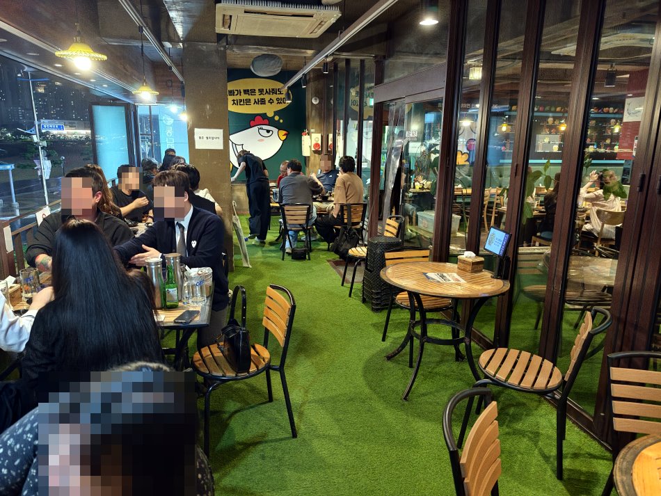 夜晚店內坐滿用餐饕客與韓國年輕人,在溫暖燈光與草皮上吃雞小酌氣氛歡樂