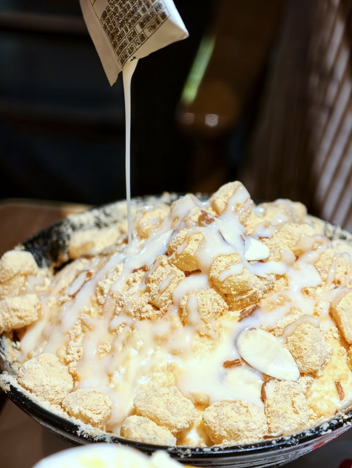 舀起一匙吸飽煉乳與黃豆粉、質地綿密黏稠的牛奶雪花冰特寫