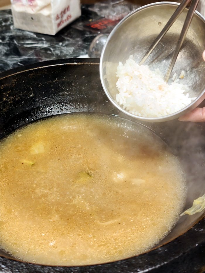 白飯倒入精華石頭火鍋湯底熬煮海鮮雜炊