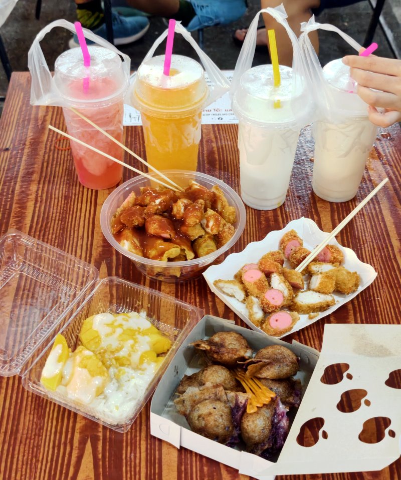 擺滿芒果糯米飯、炸物小吃、椰奶甜點與現打冰沙的豐富夜市餐桌