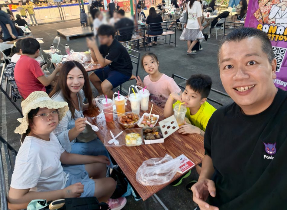 全家人在夜市用餐區桌旁手拿美食冰沙開心自拍