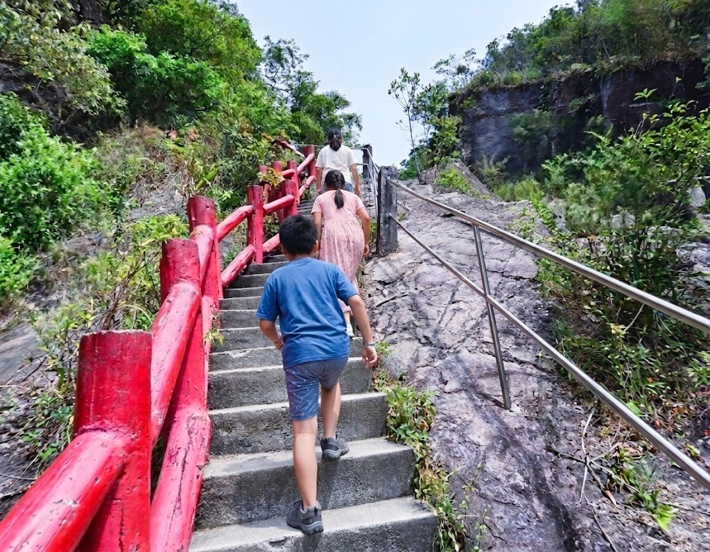 小朋友穿著運動鞋沿著階梯挑戰爬上猴洞坑瀑布頂端