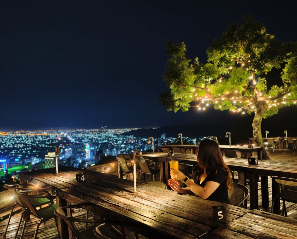 必拍角度：坐在木桌旁手持飲品凝望夜景的唯美側影