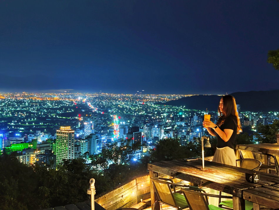 必拍角度：觀景台前緣手持飲品眺望礁溪市區金黃光軌