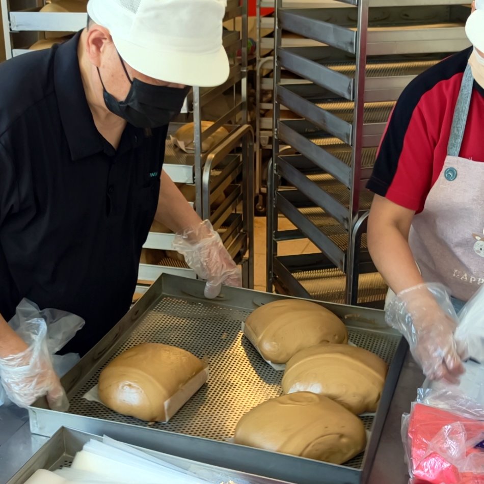 剛蒸出爐、油亮飽滿的大城黑糖饅頭放置在不鏽鋼蒸盤上