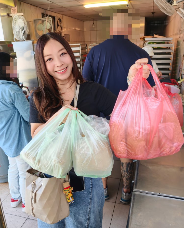 開心地提著兩大袋剛買到的大城黑糖饅頭合影