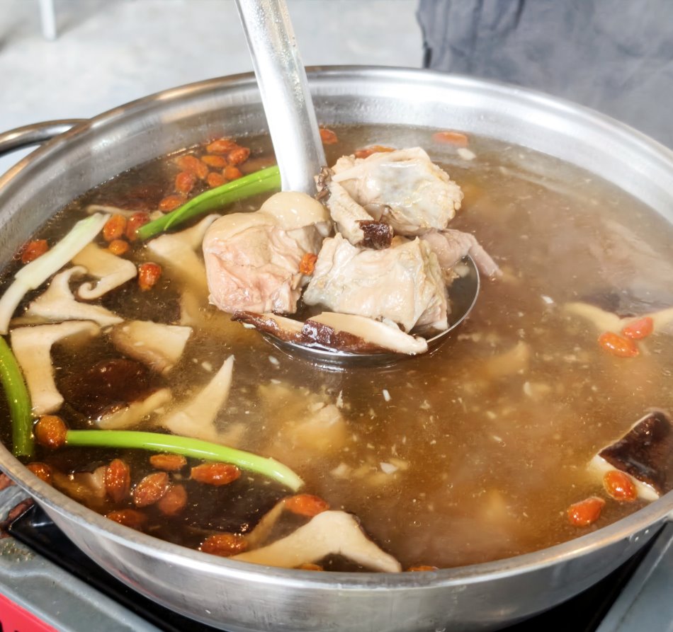 湯匙舀起滿滿的香菇、軟綿蒜頭與大塊雞肉真材實料