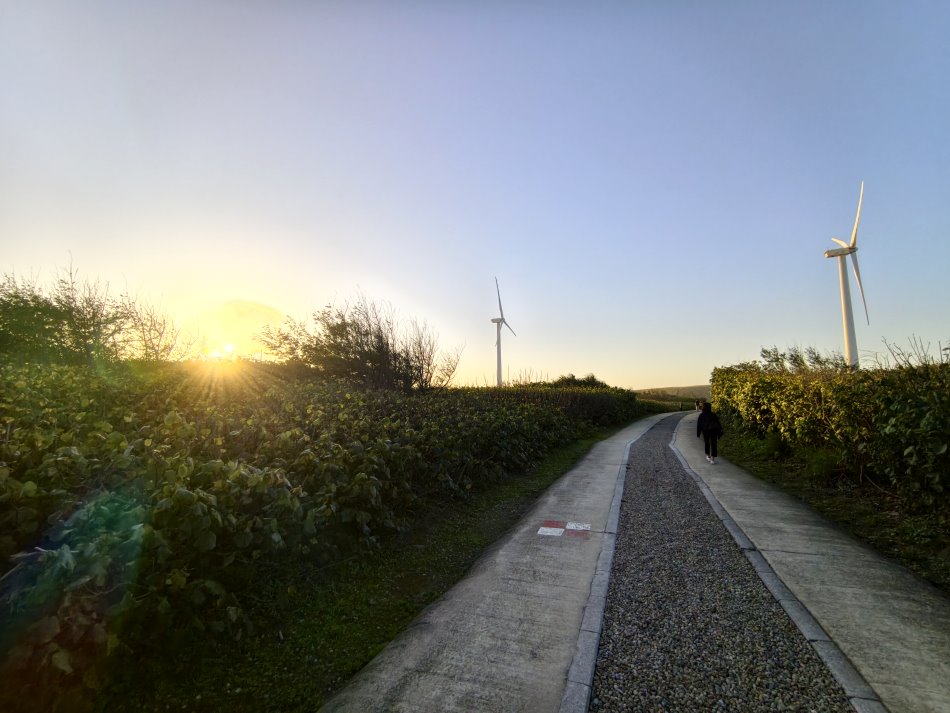 草漯沙丘巨大風力發電機葉片與金黃暮色天空