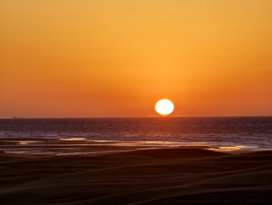 太陽沉入海平面的半圓金紅餘暉最後謝幕