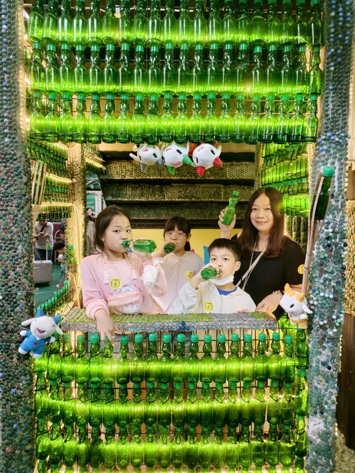 全家人在綠色玻璃汽水瓶造景牆前乾杯合照