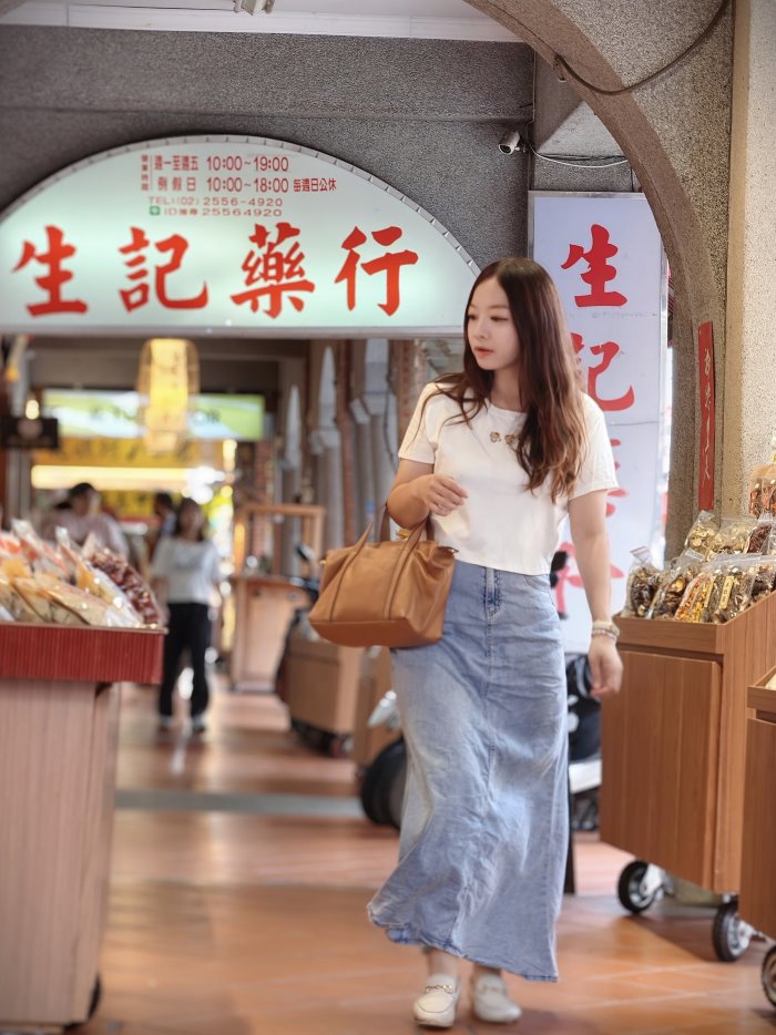 迪化街生記藥行紅磚拱門騎樓下，單手手提焦糖棕托特包採買乾貨