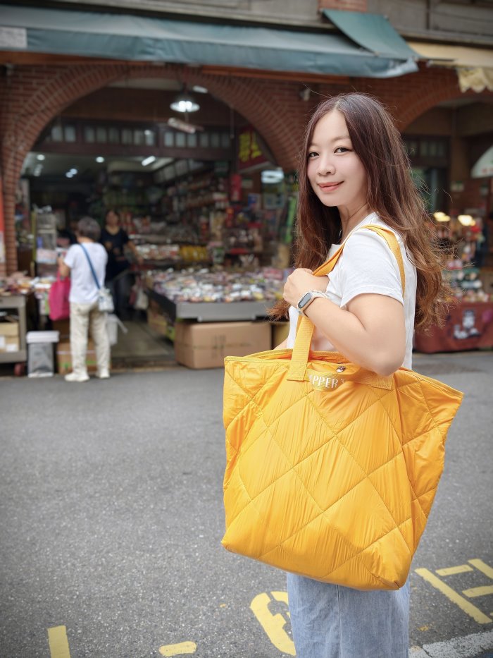 大稻埕迪化街中藥行前，單肩背亮黃色超輕量菱格絎縫旅行袋採買
