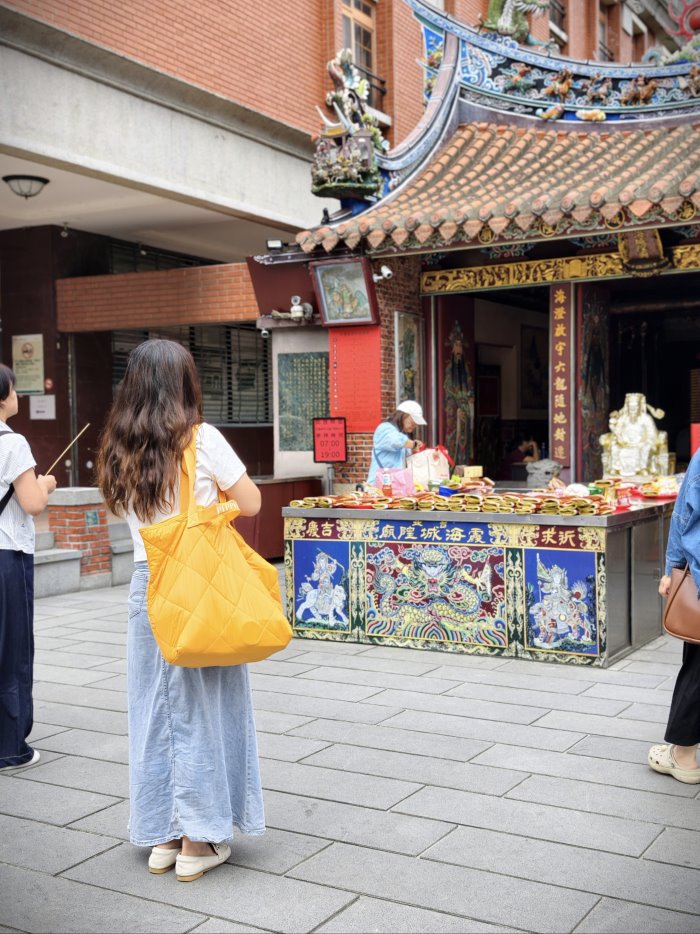 台北霞海城隍廟前參拜祈福背影，身背 PEPPERS 橘黃色大容量輕便旅行袋