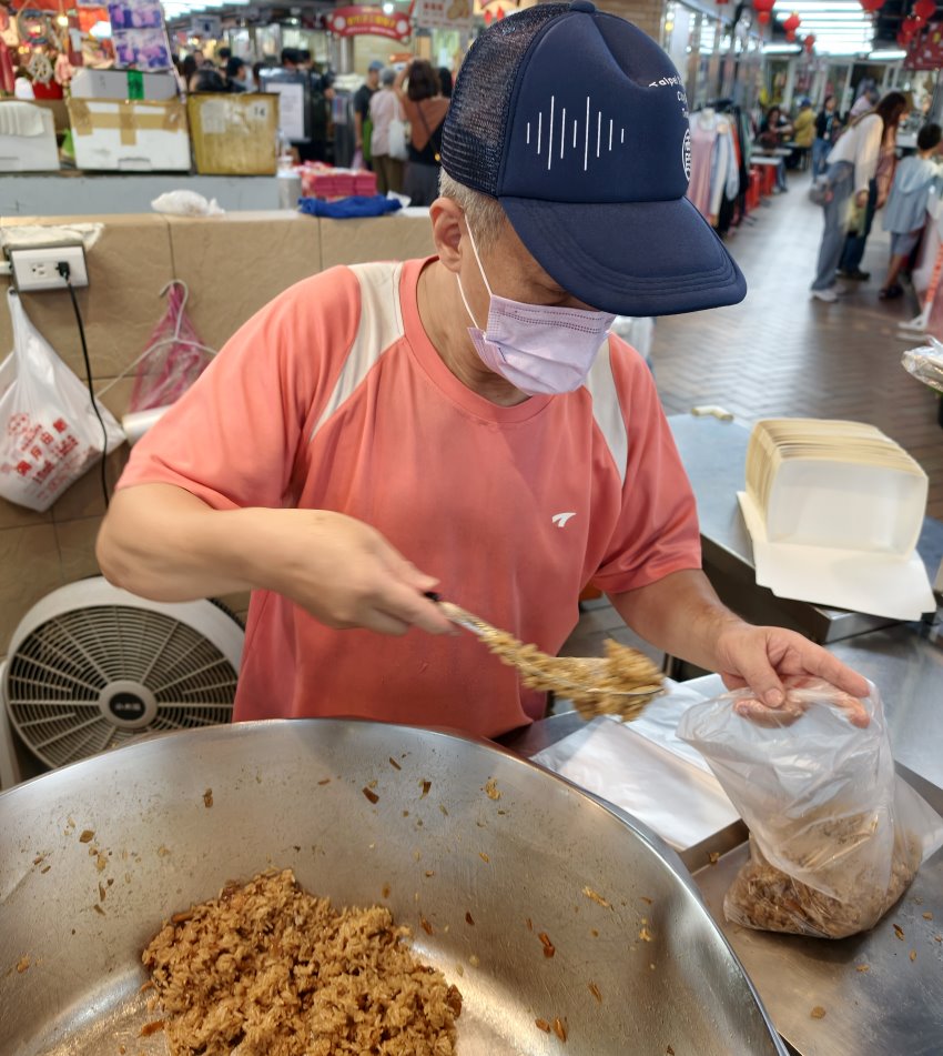 工作人員熟練舀起最後一鍋油飯裝入耐熱塑膠袋