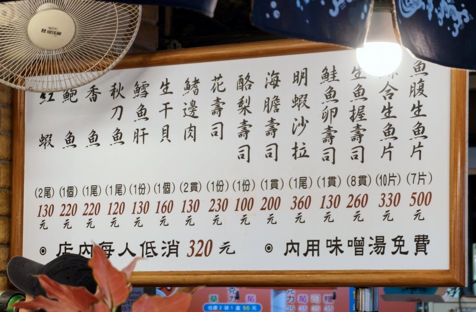 丸隆生魚行吧台上方的木質菜單與低消公告
