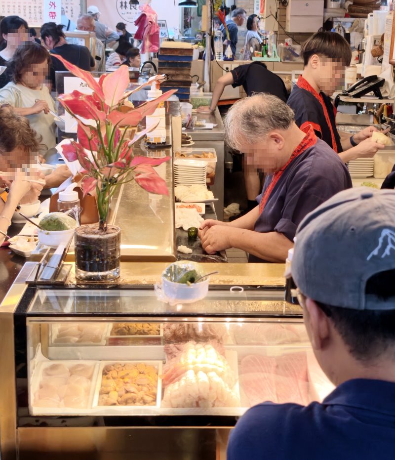 丸隆生魚行師傅在冷藏櫃後俐落捏製生魚握壽司